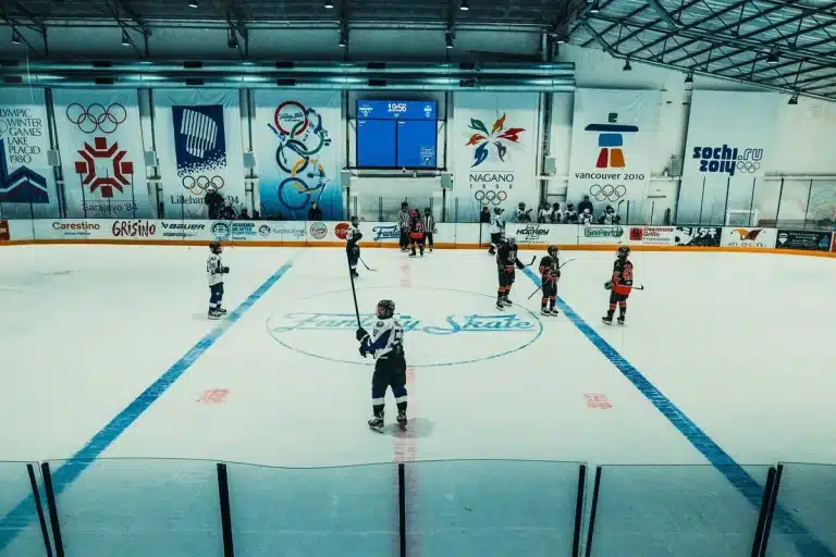 Two anonymous figures in tense standoff inside a hockey arena with dramatic lighting