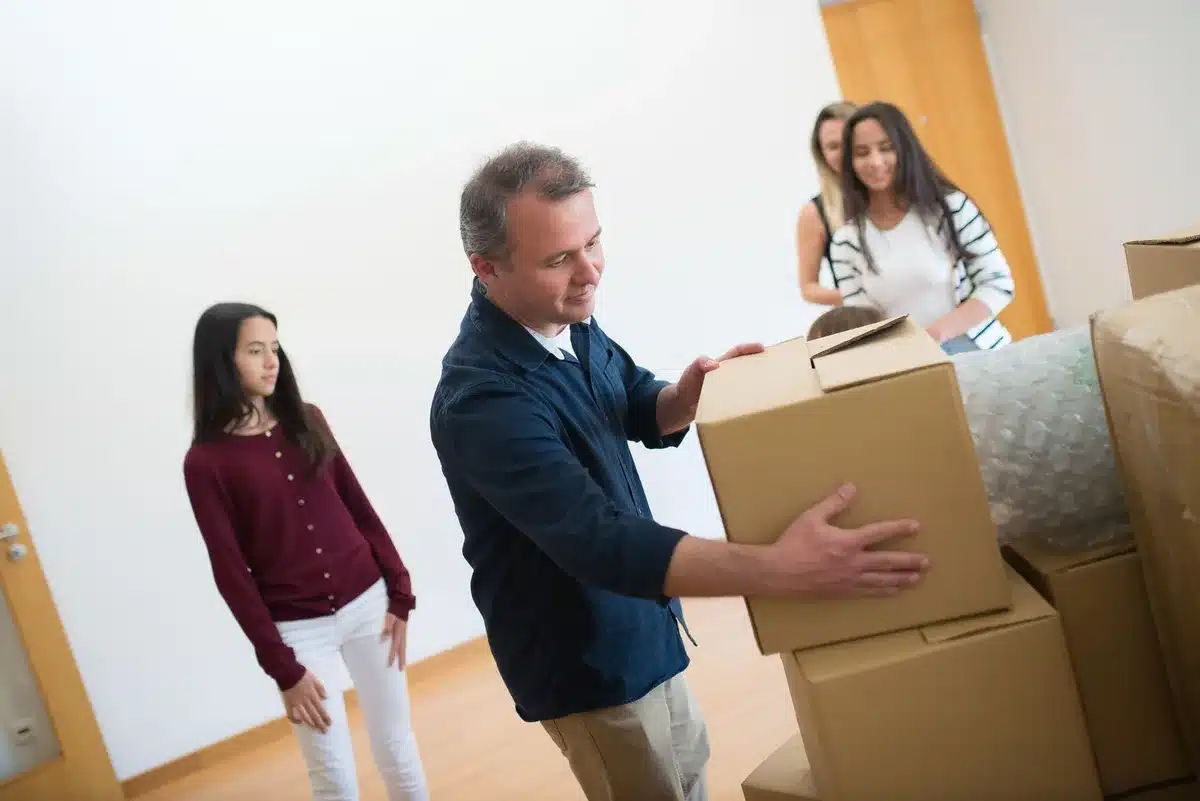 Teen unpacking boxes and belongings in a new bedroom, beginning a fresh chapter.