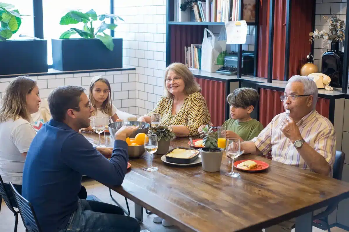 Teenagers and family members sharing a meal together at a dinner table in a warm, welcoming home setting.