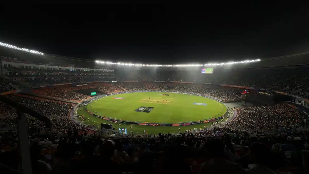 Live cricket match broadcast in stadium with crowd