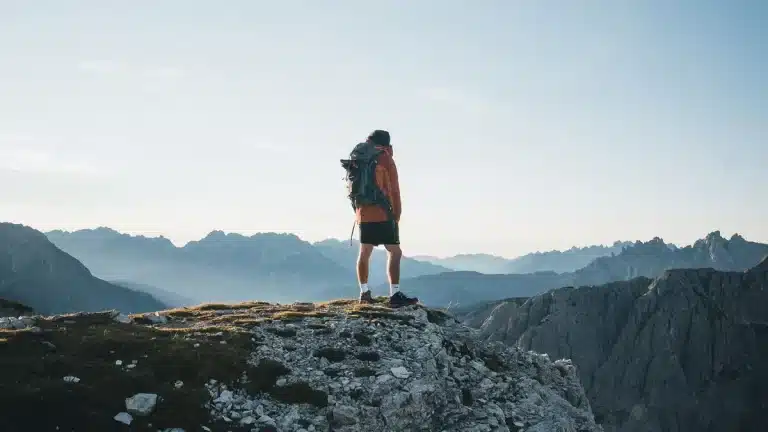 Silhouette of a climber ascending a snow-covered mountain peak at dawn with an ice axe