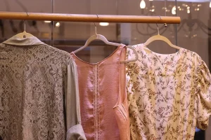 Shop employee arranging patterned textiles on a wooden display table in a bright boutique