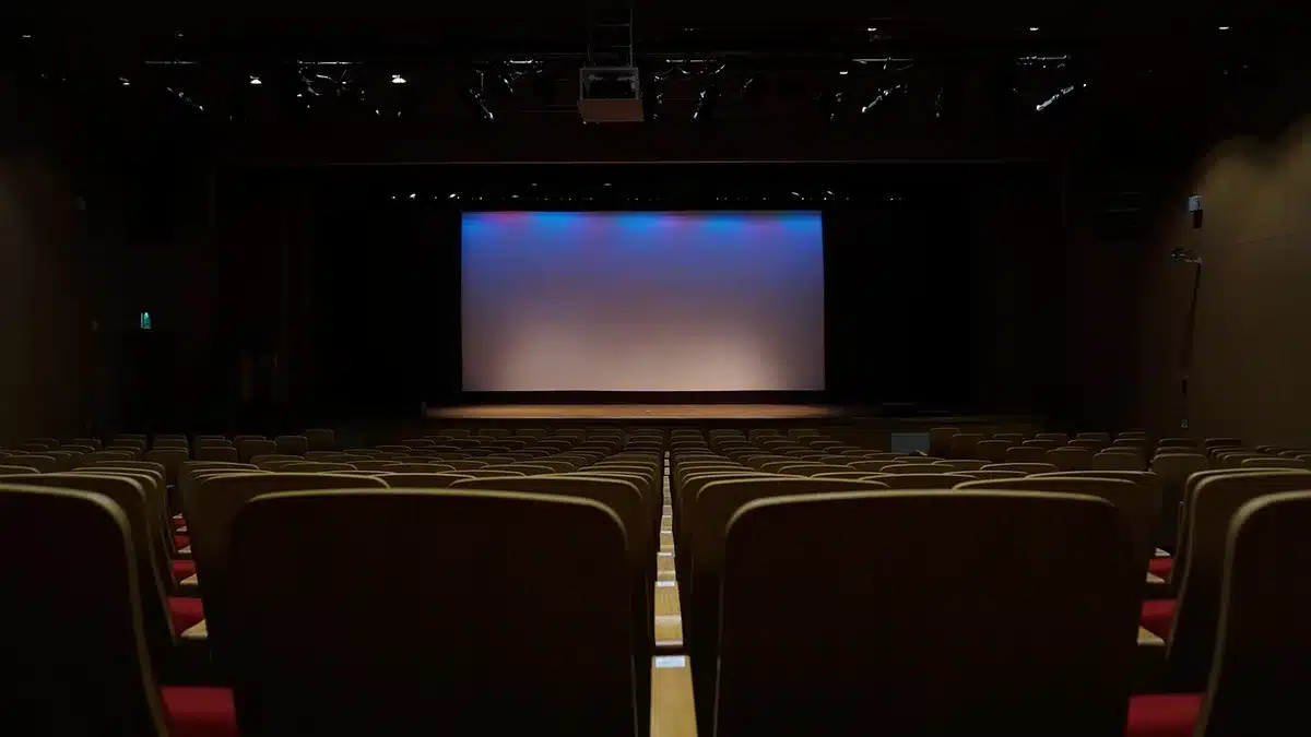 Empty movie theater seats and a dim screen representing box-office uncertainty