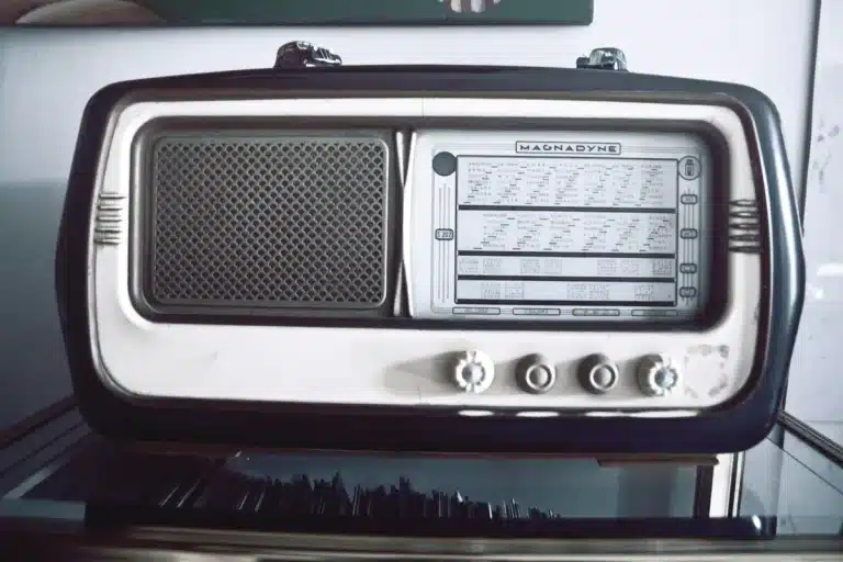 Anonymous group around a vintage radio and suitcase on a wartime street, silhouetted