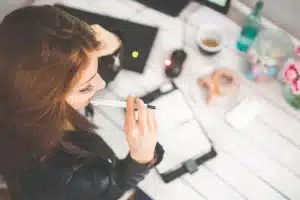 Couple coordinating schedules at a kitchen island with calendar and laptop, backpacks in background