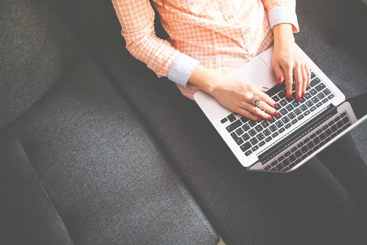Hands typing on laptop with financial reports and coffee on office table