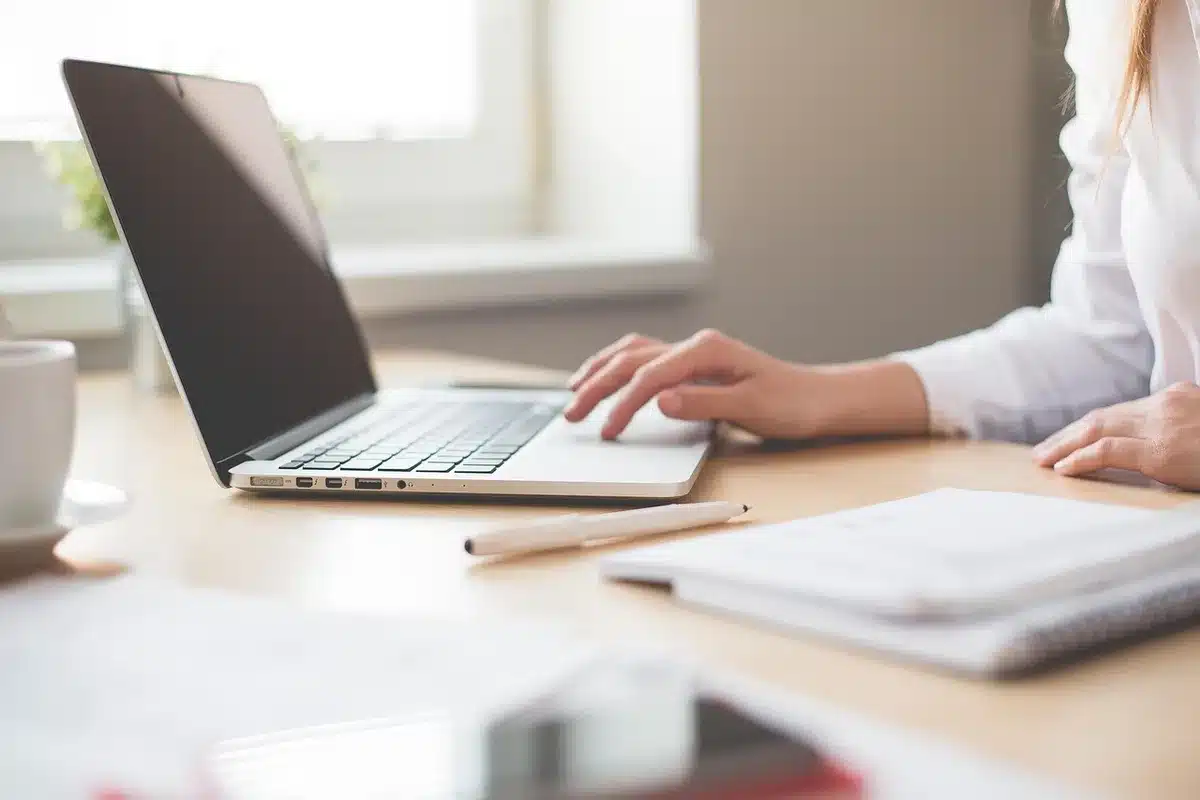Older woman at a desk with laptop beside caregiving items