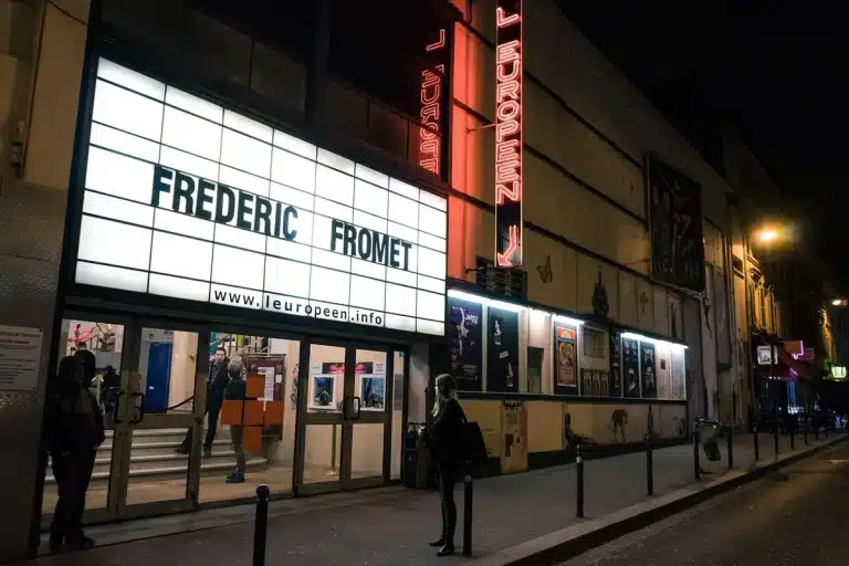 Anonymous crowd in a cinema lobby with concession stand and blurred marquee