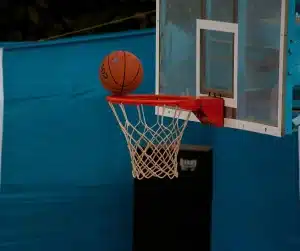 Empty indoor basketball court with sneakers and ball at the sideline