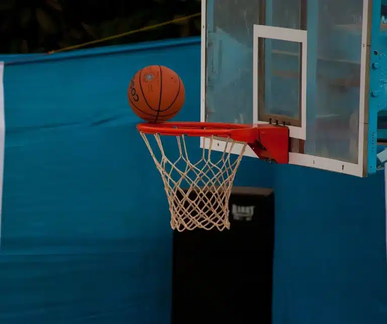 Empty indoor basketball court with sneakers and ball at the sideline