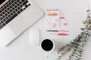 Hands, notebook and laptop on an interview desk in a modern office